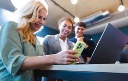 Three colleagues around a laptop and phone