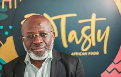 Image of Michael Olaleye, founder and managing director of Tasty African Food, in front of a blurred sign reading Tasty African Food