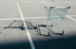 An empty shopping cart casts a shadow over an empty car park