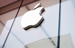 A close up shot of the outside of an Apple office with its logo displayed on front.