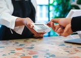 A person taps their payment card on a handheld card reader