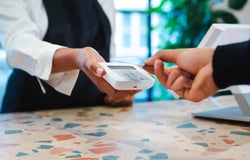 A person taps their payment card on a handheld card reader