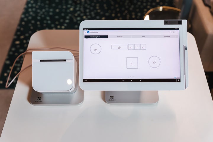 A white Clover POS setup, including a white printer on the left and white terminal on the right, on a white surface
