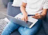 Online shopping, laptop or hands with credit card for financial digital payment while relaxing on sofa at home. Zoom, finance or girl typing ecommerce subscription discount code, sales offer or deal.