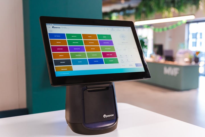 The black Epos Now POS terminal on a white surface. The screen is showing different categories in a range of colours