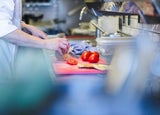 A chef prepares fresh vegetables on a chopping board