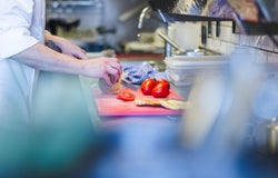 A chef prepares fresh vegetables on a chopping board