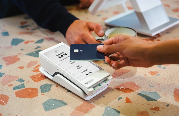 A person taps their payment card on a POS device
