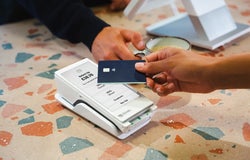 A person taps their payment card on a POS device