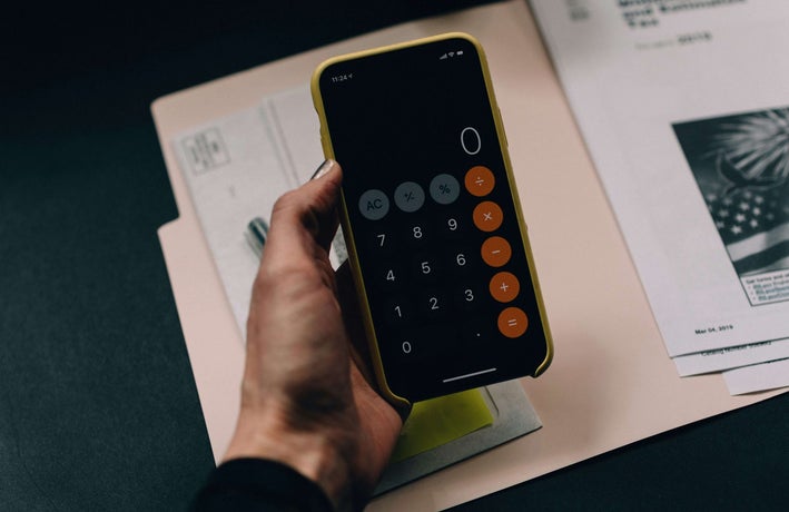 A hand holds a smartphone with a the calculator app open.