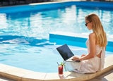 Woman sitting at a pool working on her laptop