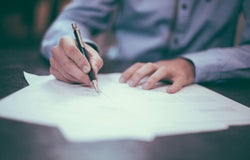 A person is signing a contract with a pen.